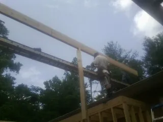 Carpenter setting a ridge beam over a new addition frame — Ice Dam Removal by Roofing Brothers in Spiritwood