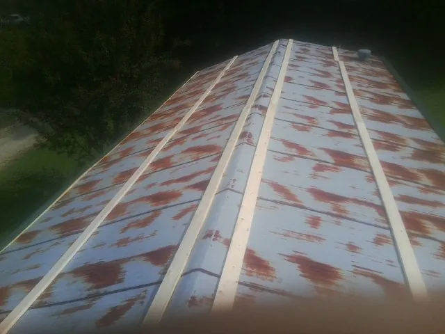 Rusted metal roof panels with new wood purlins before replacement — Storm Damage Roof Repair in Spiritwood by Roofing Brothers