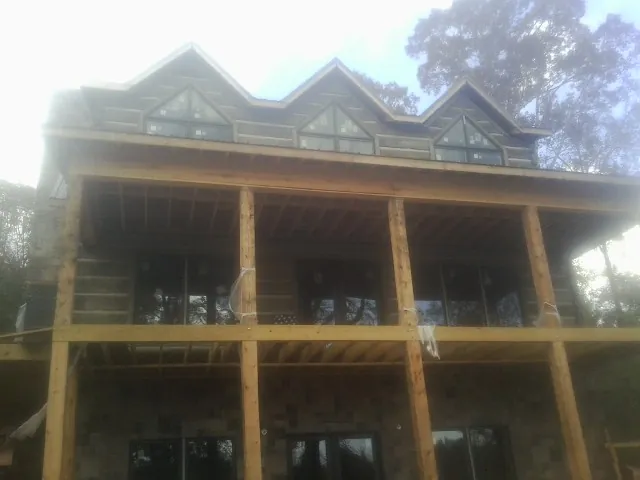Dormers and porch framing on a large log home under construction — Roof Coating work by our crew in Spiritwood
