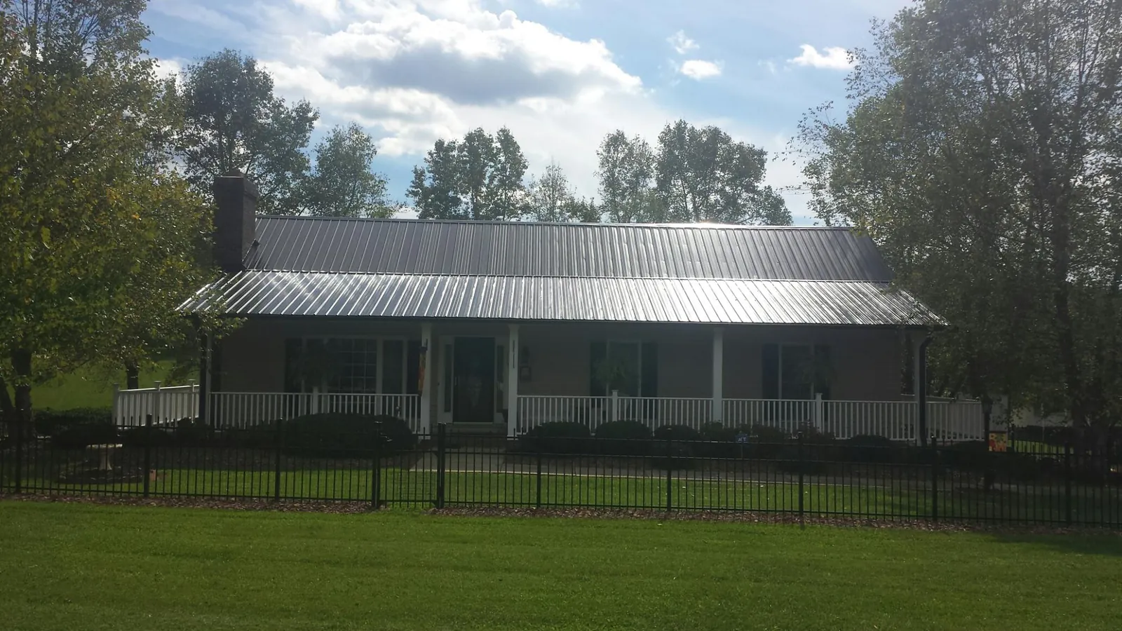 Gray metal roof on a brick ranch with a full width front porch — Gutter Guard Installation work by our crew in Spiritwood