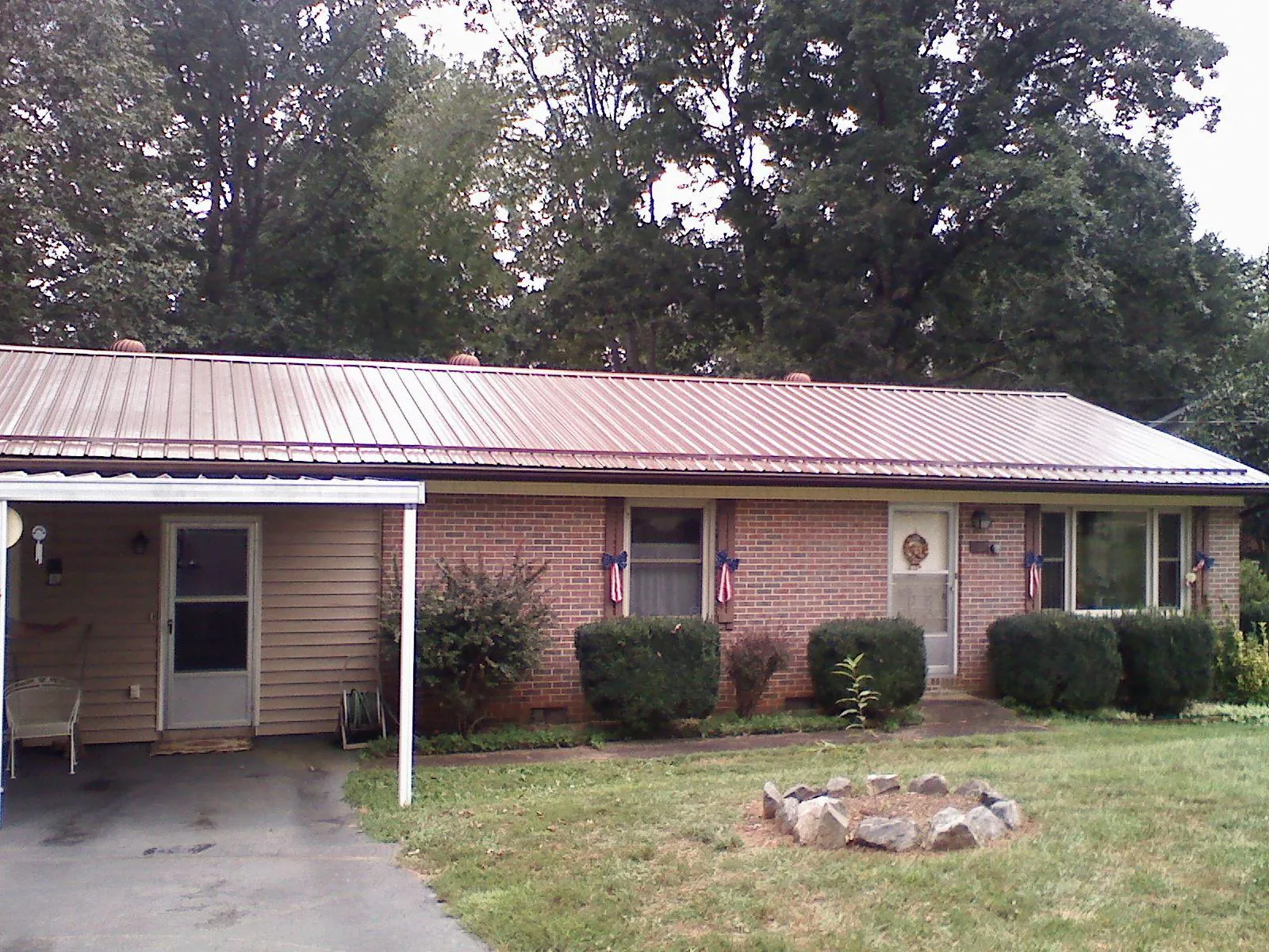 Bronze metal roof and carport on a brick ranch home — Roof Repair work by our crew in Spiritwood