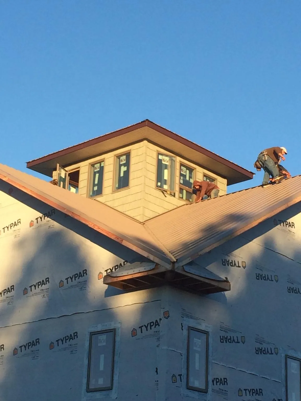 Roofers working around a rooftop cupola on a new metal roof at sunset — Roof Waterproofing in Spiritwood by Roofing Brothers